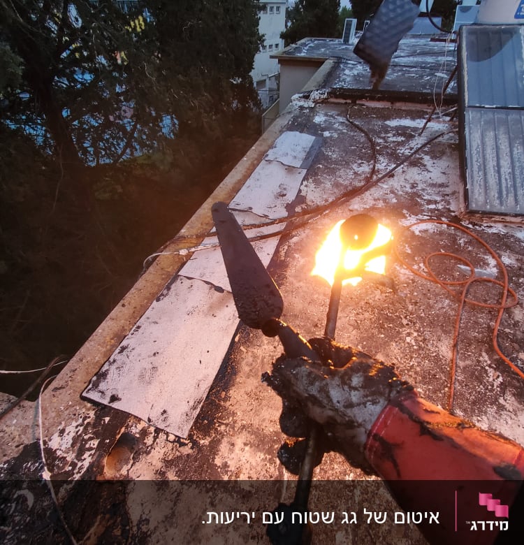 אדם עם כפפה אוחז במבער על גג